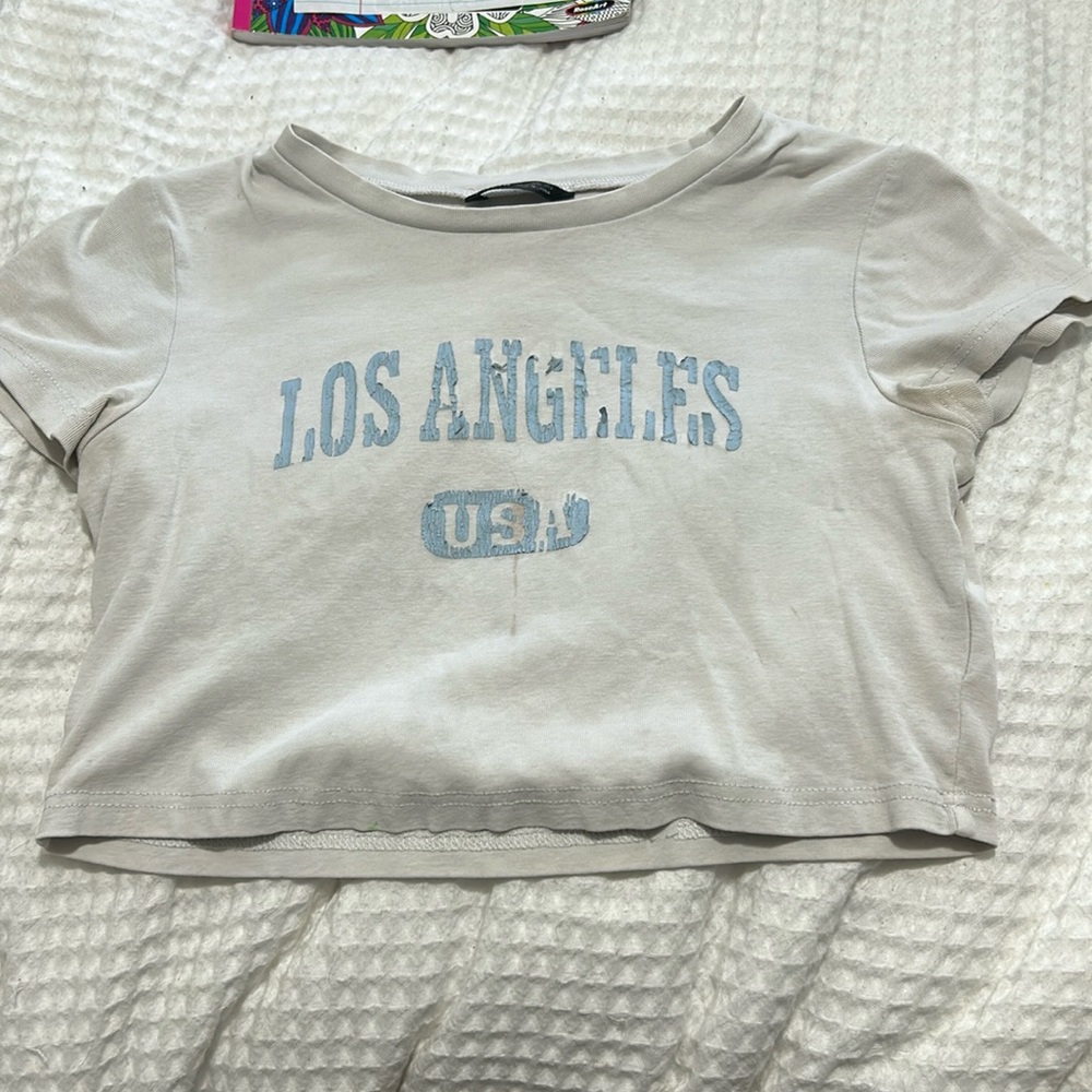 A white crop top with lettering saying Los Angeles USA in the color blue